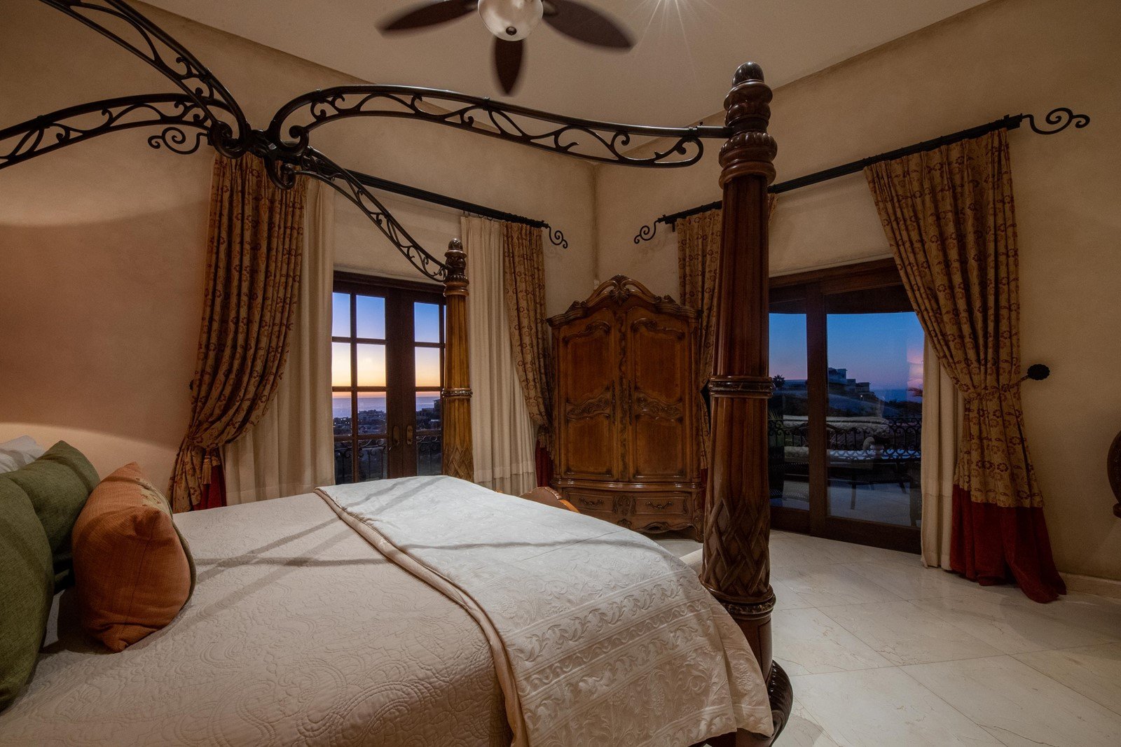 A bedroom with two balcony doors and views of the ocean.