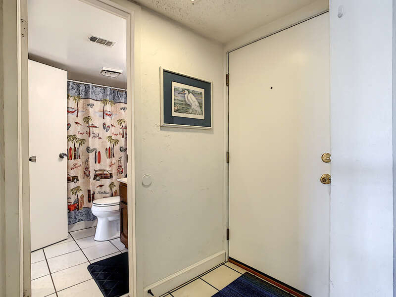 Two doors, one leading into bathroom with beach-themed shower curtain.