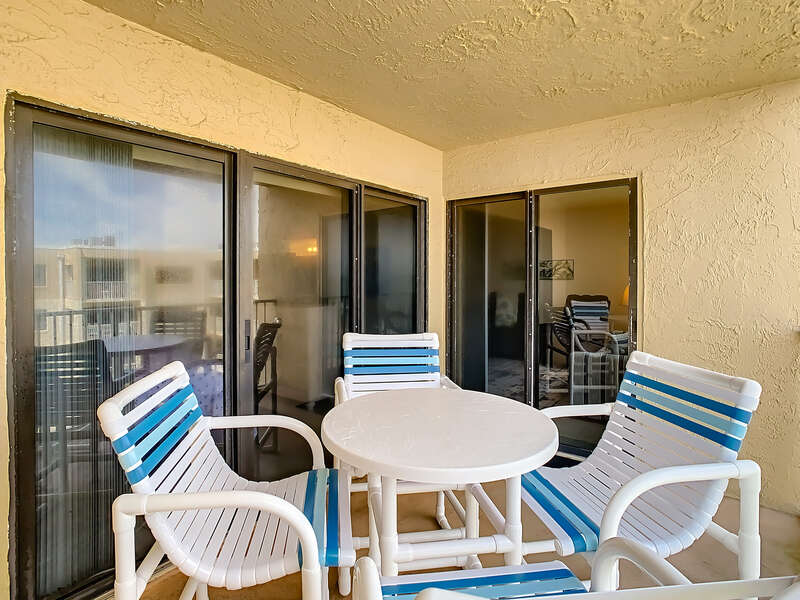 Small white table surrounded by four pool chairs.