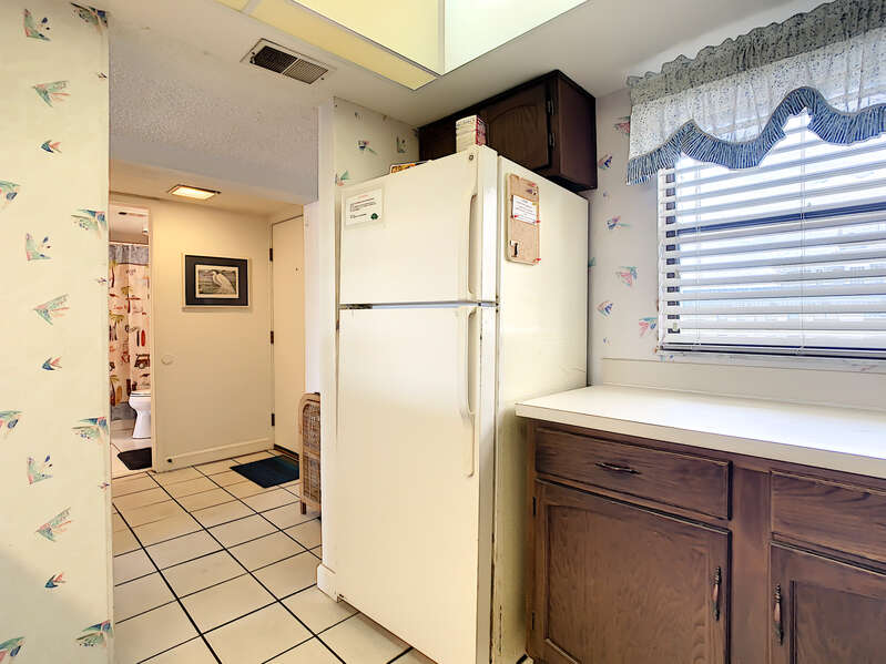 Refrigerator next to off-white countertop with tiled floor