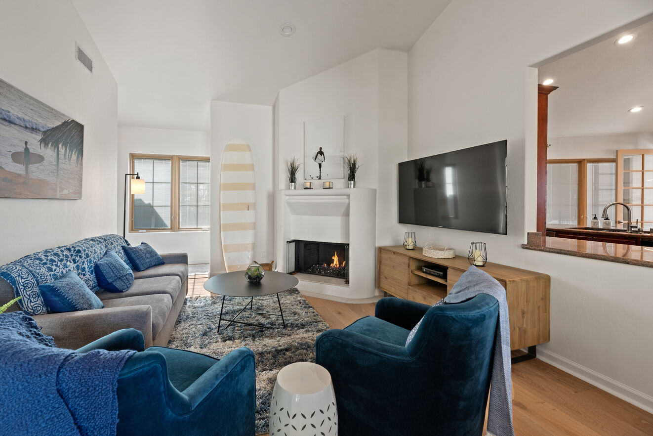 Cozy family room with a Queen size sleeper sofa, lots of comfortable seating, large flat screen smart tv and modern glass fire in a traditional 40's style corner fireplace.