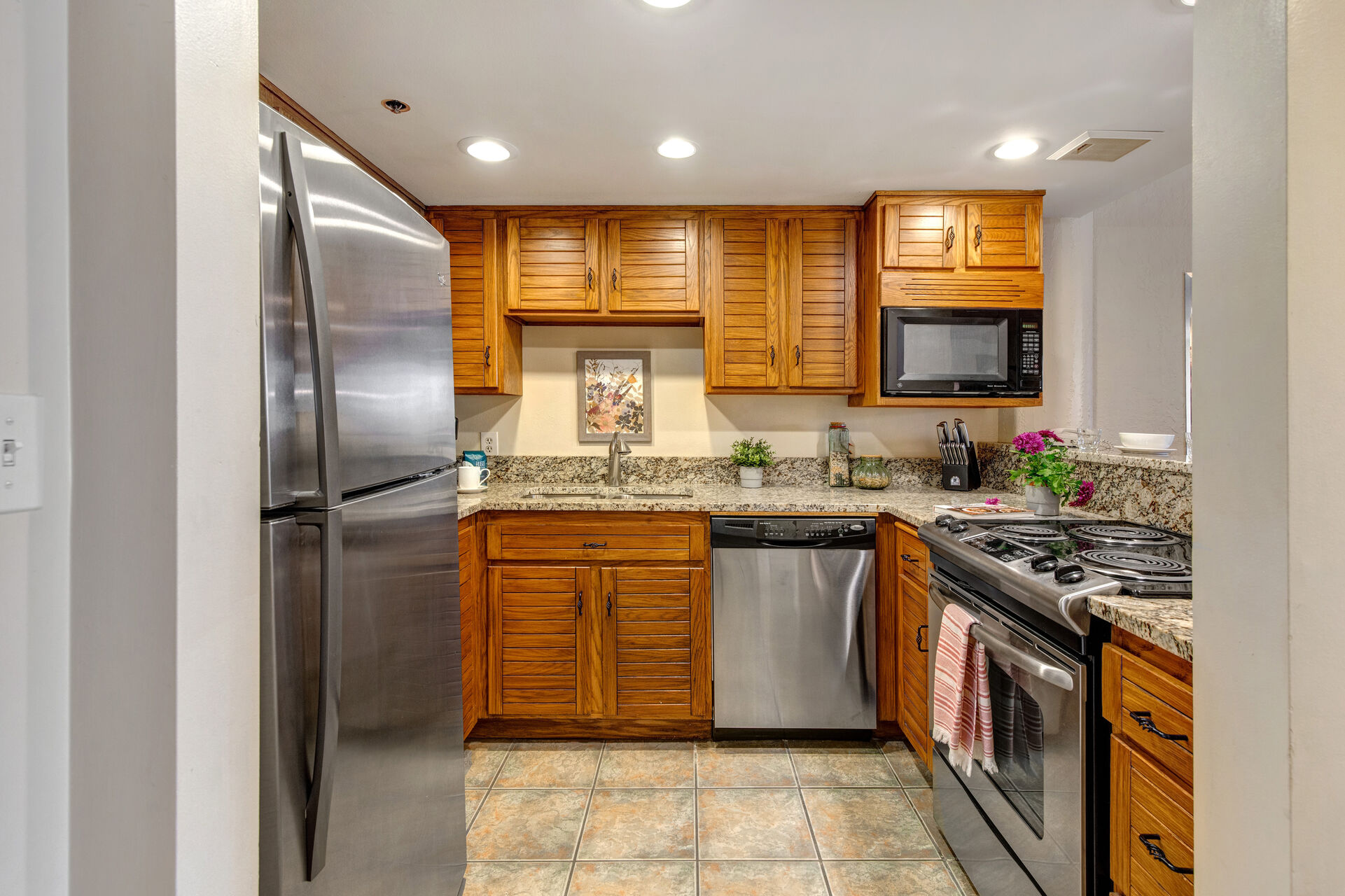 Fully Equipped Kitchen with stone countertops, stainless steel appliances, and bar seating for three
