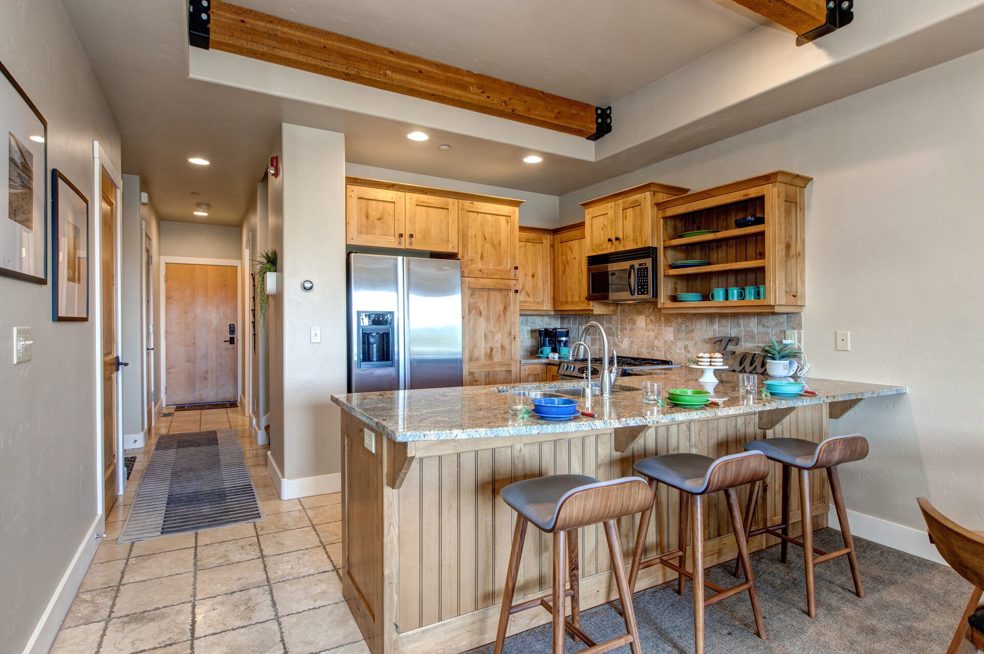 Fully Equipped Kitchen with stone countertops, stainless steel appliances, ice maker, and bar seating for three
