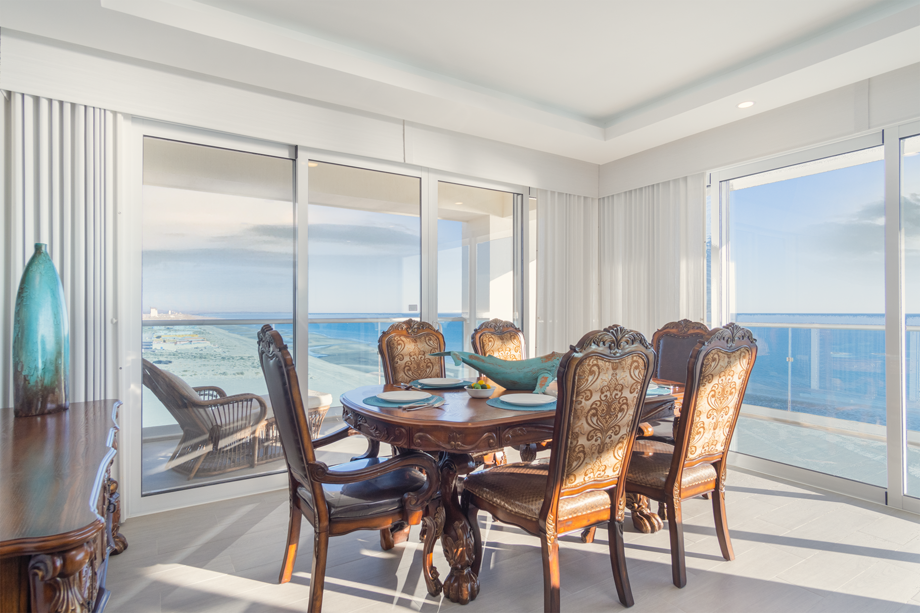 The dining table is surrounded by views of the beach.
