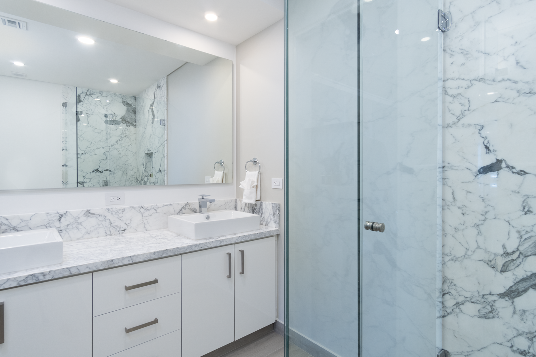 The glass shower stall with marbled walls and counter top in the main bedroom.