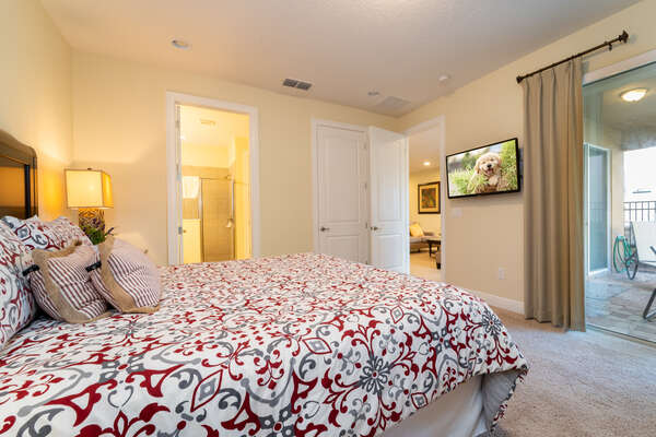 Master bedroom showing bathroom, TV and patio doors to pool area