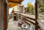 Private deck overlooking pool and surrounding mountains with seating for two and BBQ grill