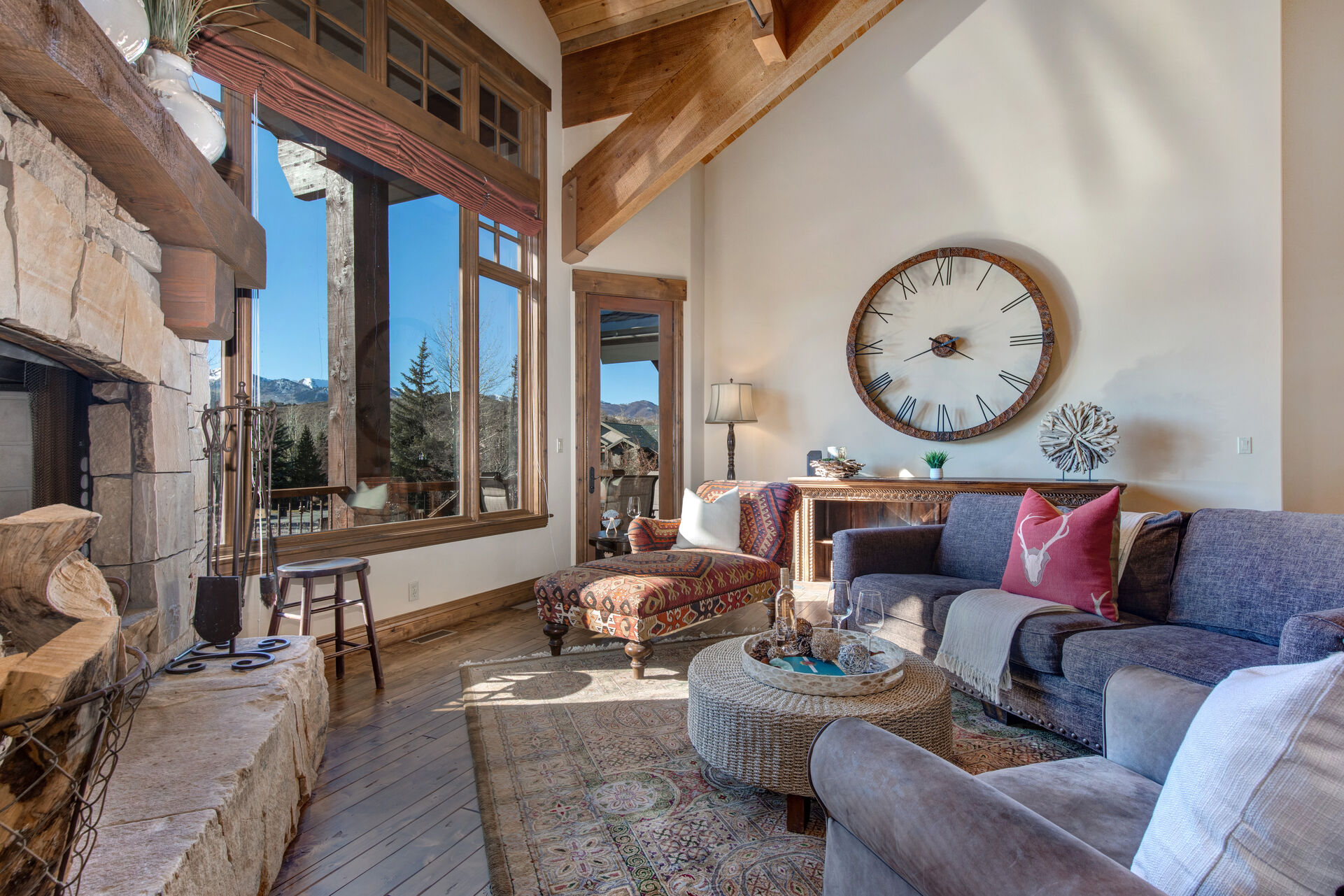 Main Level Living Room with vaulted ceilings, gas-assist fireplace, plush furnishings, wet bar access, and stunning views of the surrounding mountains