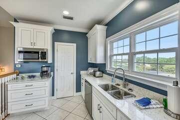 Tiled kitchen with stainless steel appliances, standard coffee maker, microwave and large pantry.