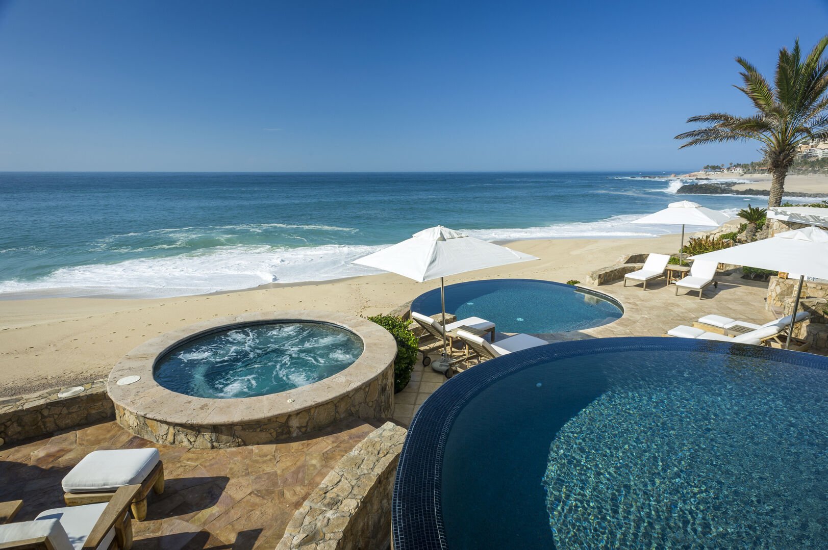 A jacuzzi and an outdoor lounge area by the beach