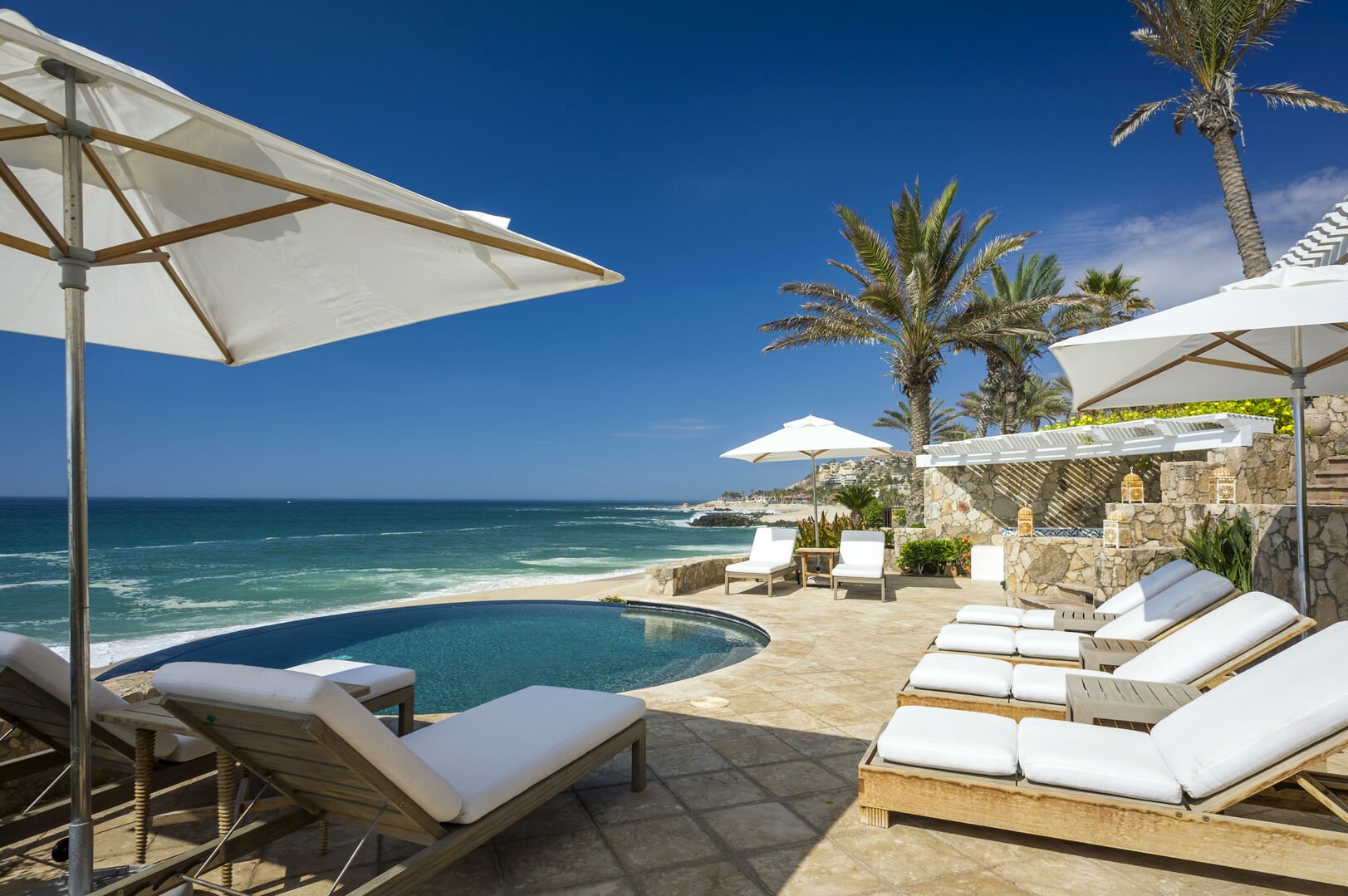 White lounge chairs by the pool overlooking the sea