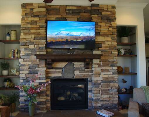 Fireplace in living room with 50 inch TCL Roku TV.