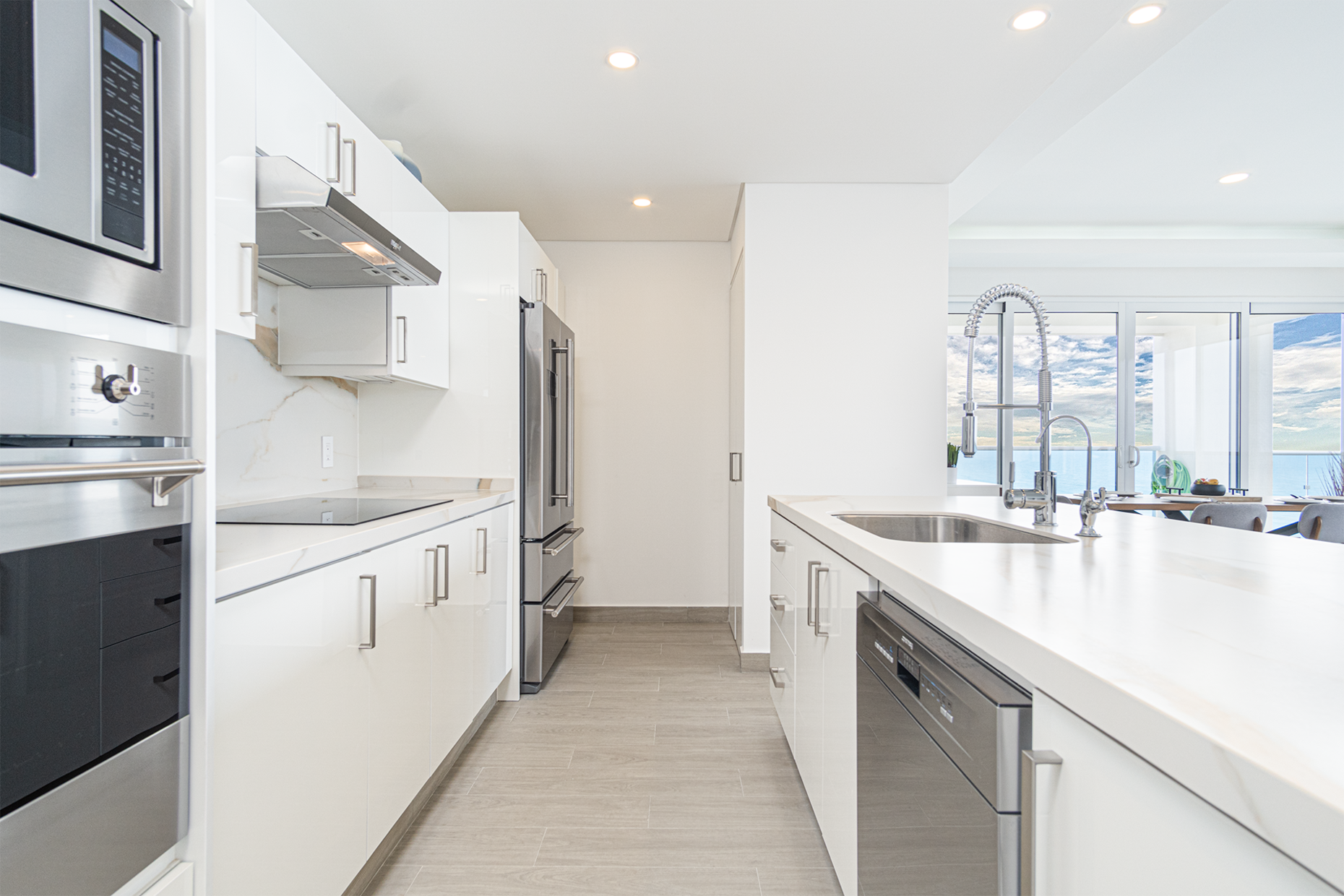 The kitchen is sleek with stainless steel appliances, and clean white cabinets.