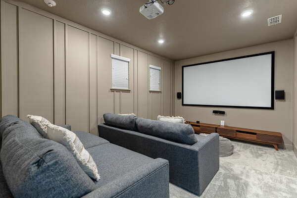 This home has its own theater space with sofa seating and a projector with a screen.