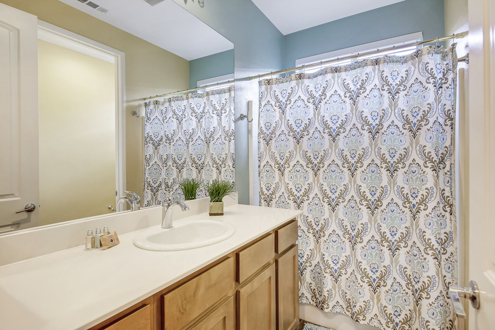 The hallway bathroom features a shower and tub combo and vanity sinks.