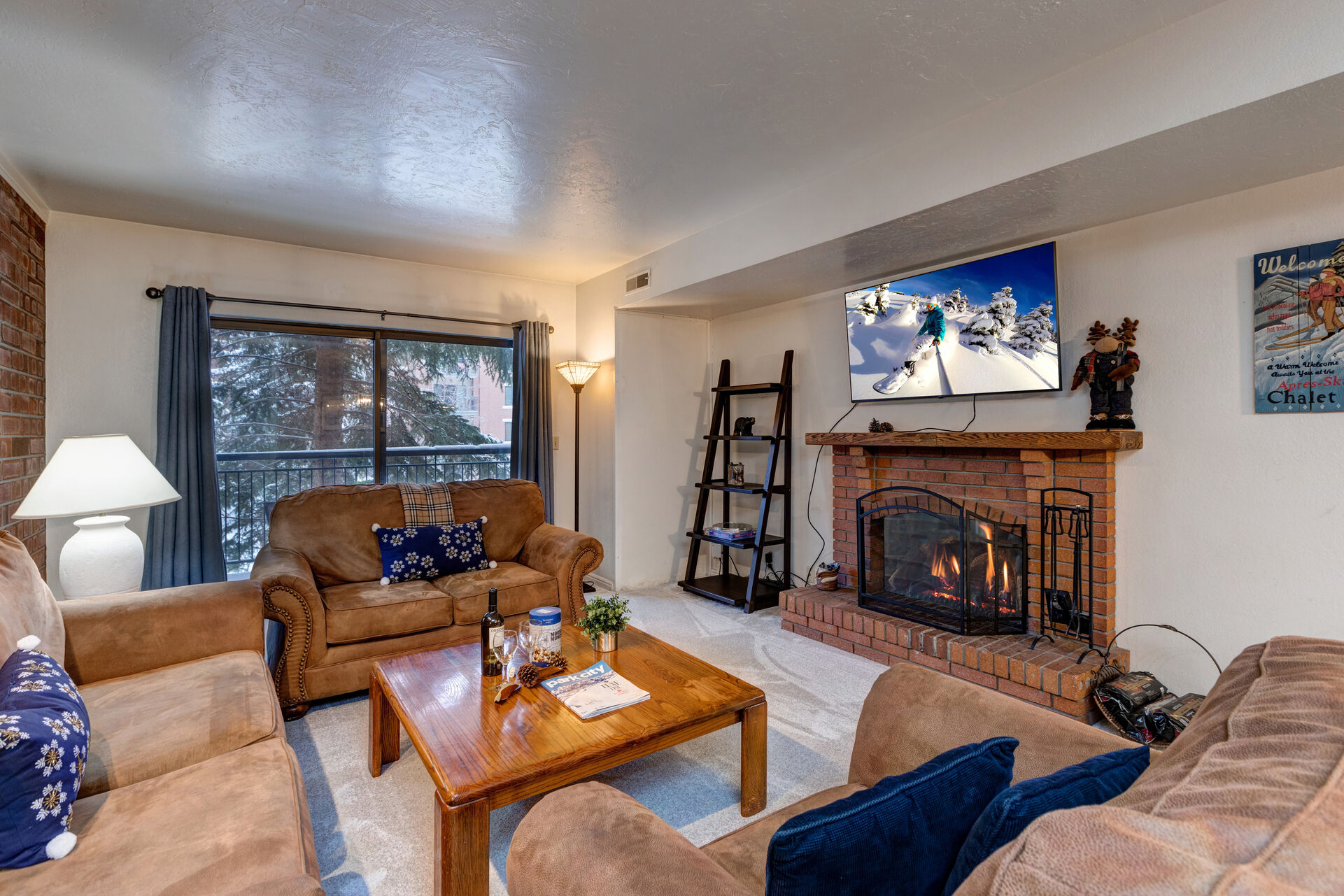 Living Room with gorgeous suede furnishings, sofa bed, wood-burning fireplace, LG smart TV, and private balcony access