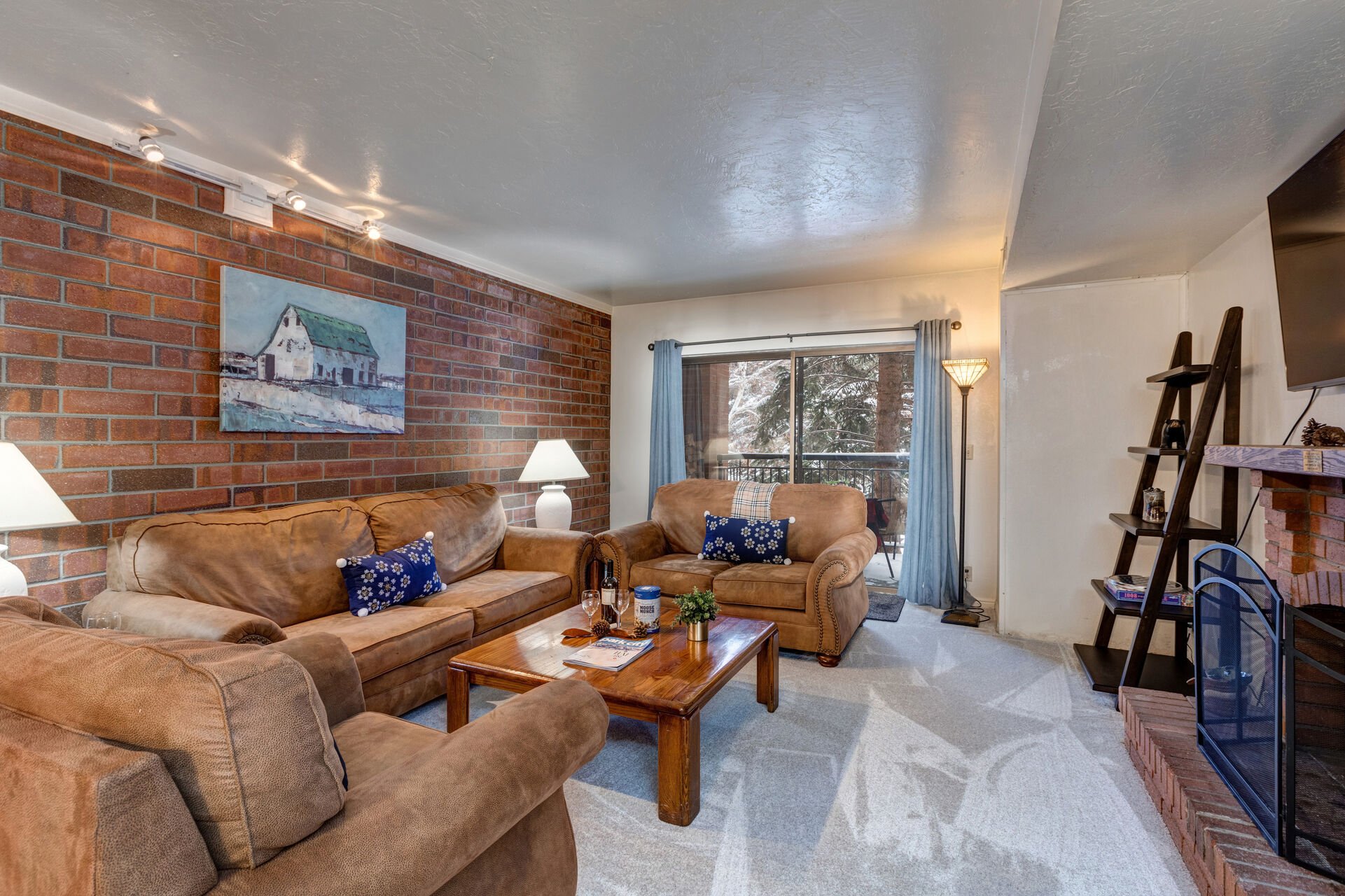 Living Room with gorgeous suede furnishings, sofa bed, wood-burning fireplace, LG smart TV, and private balcony access