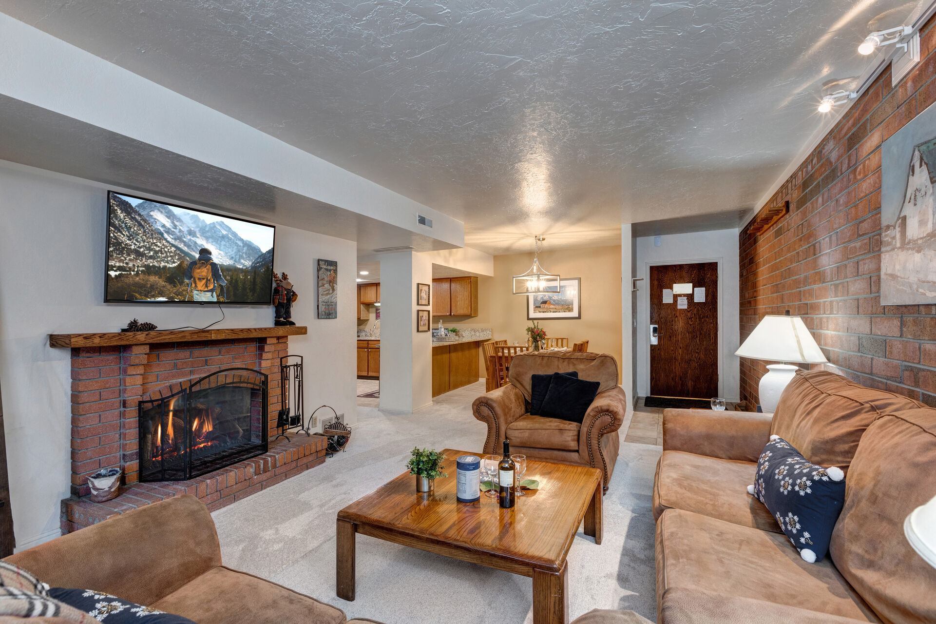 Living Room with gorgeous suede furnishings, sofa bed, wood-burning fireplace, LG smart TV, and private balcony access