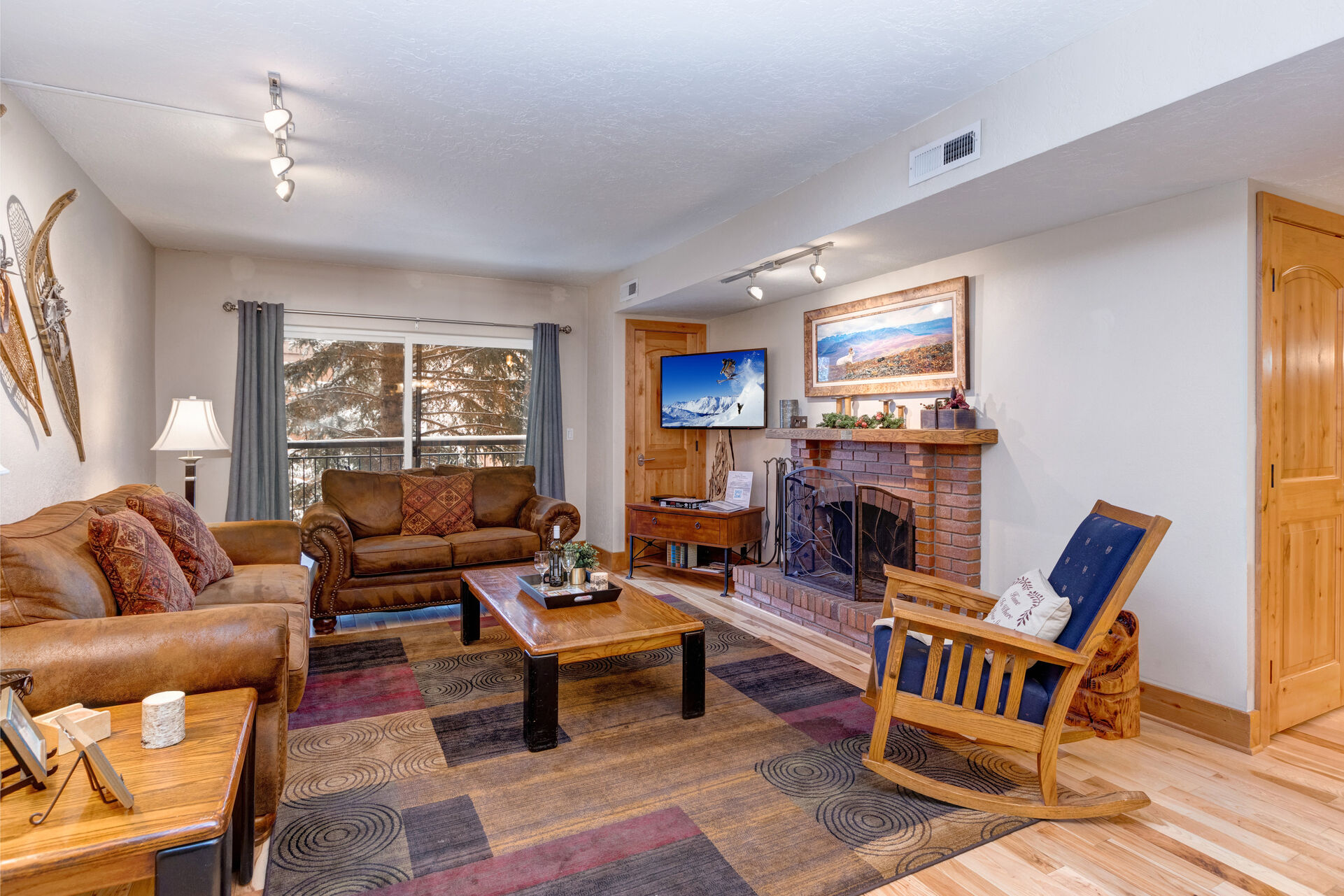 Living Room with gorgeous suede furnishings, sofa bed, wood-burning fireplace, Samsung smart TV, and private balcony access