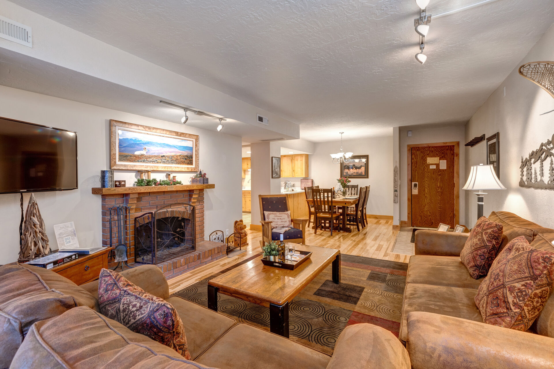 Living Room with gorgeous suede furnishings, sofa bed, wood-burning fireplace, Samsung smart TV, and private balcony access