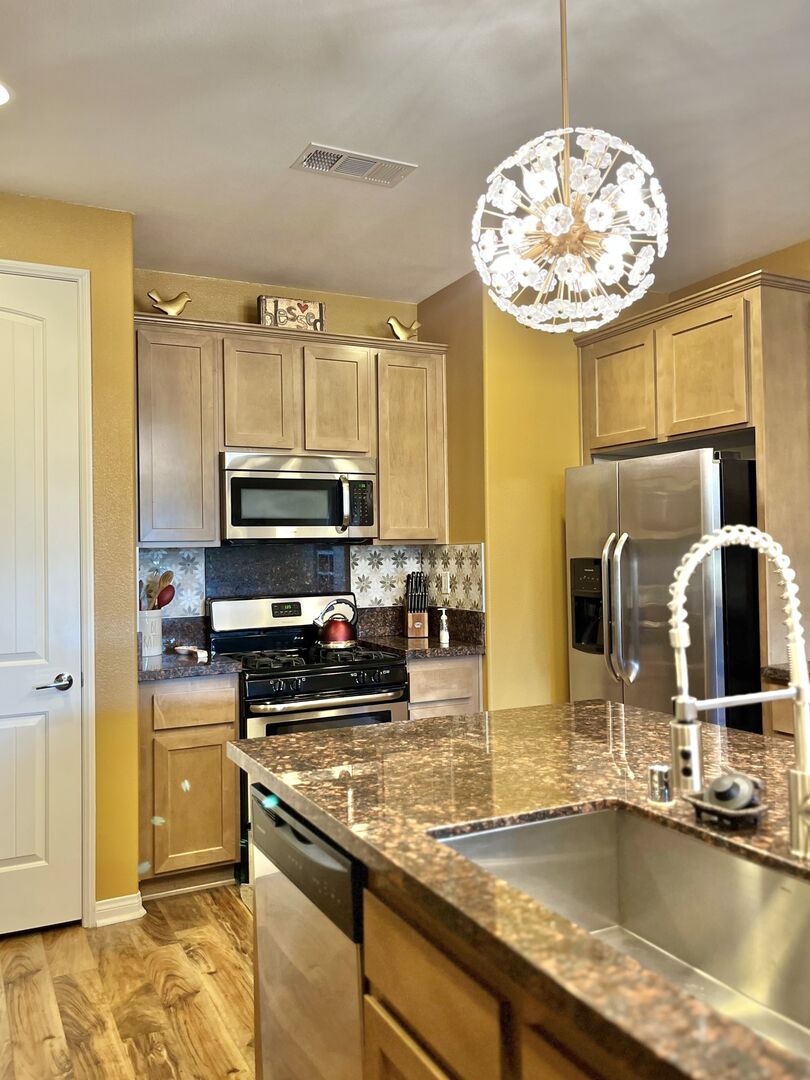 The fully-equipped kitchen features stunning stainless steel appliances such as a Frigidaire side-by-side refrigerator.
