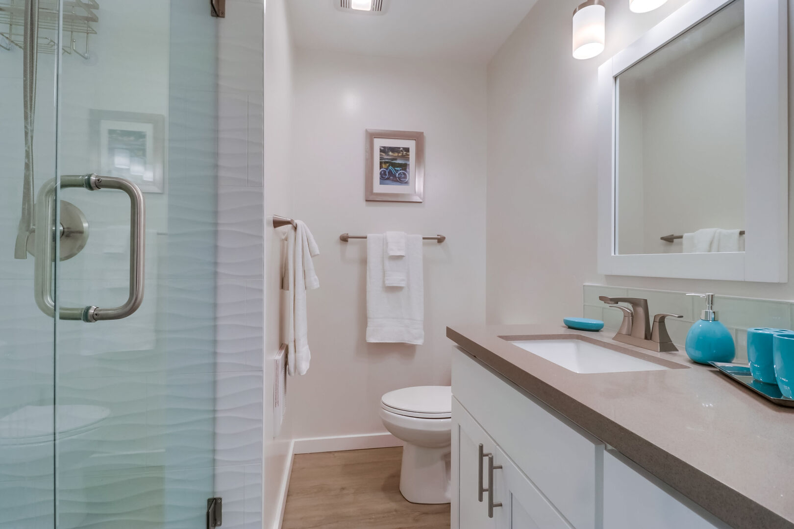 Guest bathroom with large single vanity, toilet, ample storage space and walk-in shower. Please note: the shower does have a small step to get in