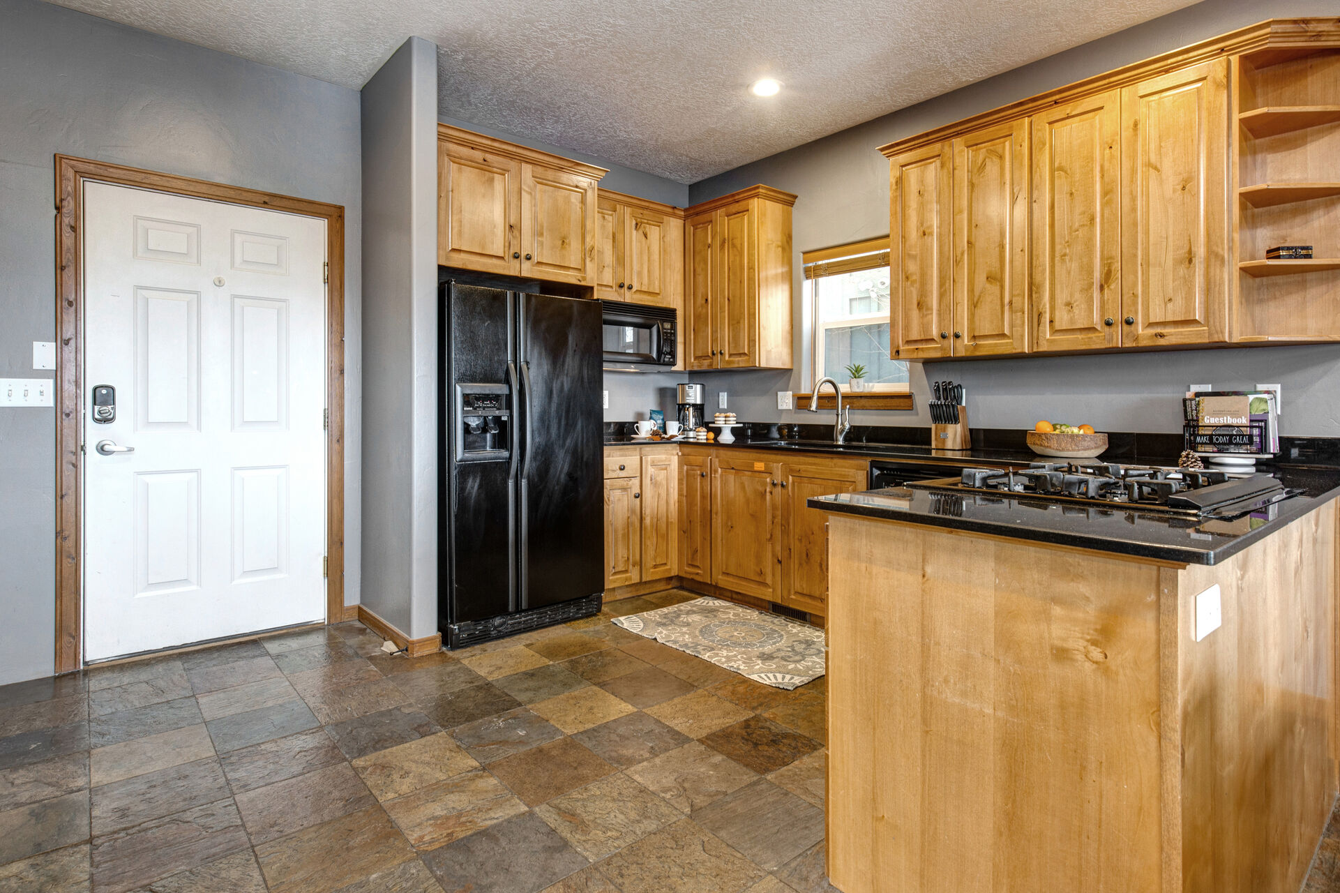 Fully quipped Kitchen with garage access, beautiful stone countertops, ample space for prep, and built-in ice maker