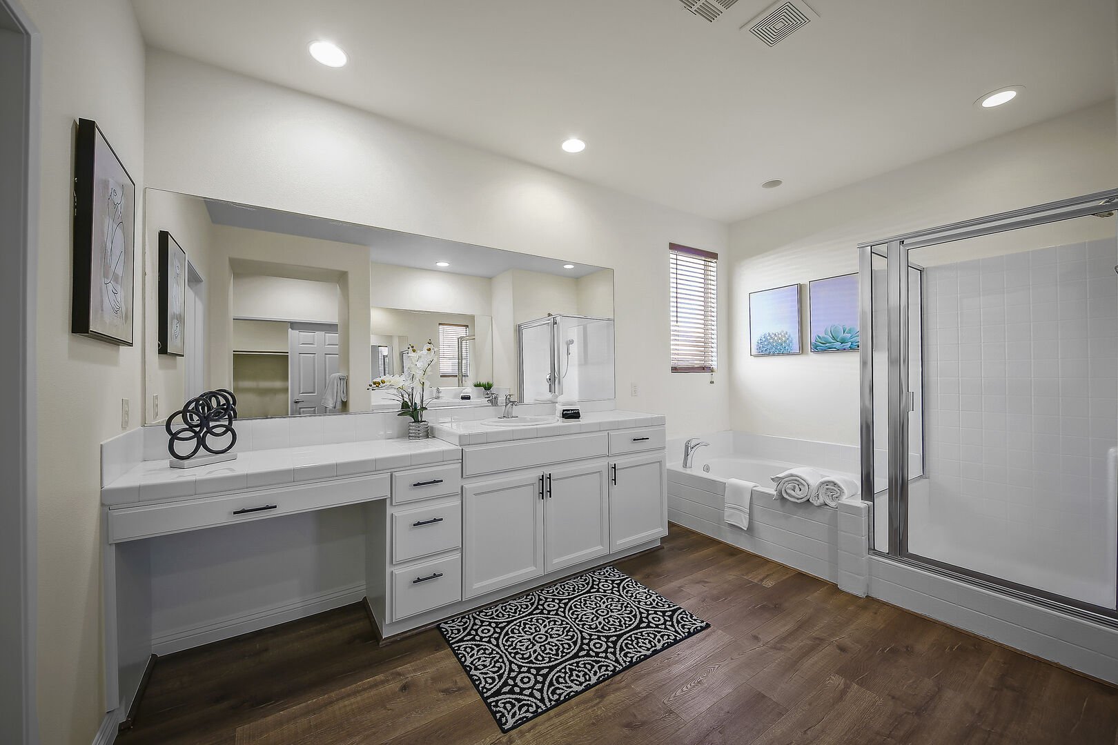 The private, en suite bathroom features a soaking tub, tile shower and his and her vanity sinks and a makeup counter.