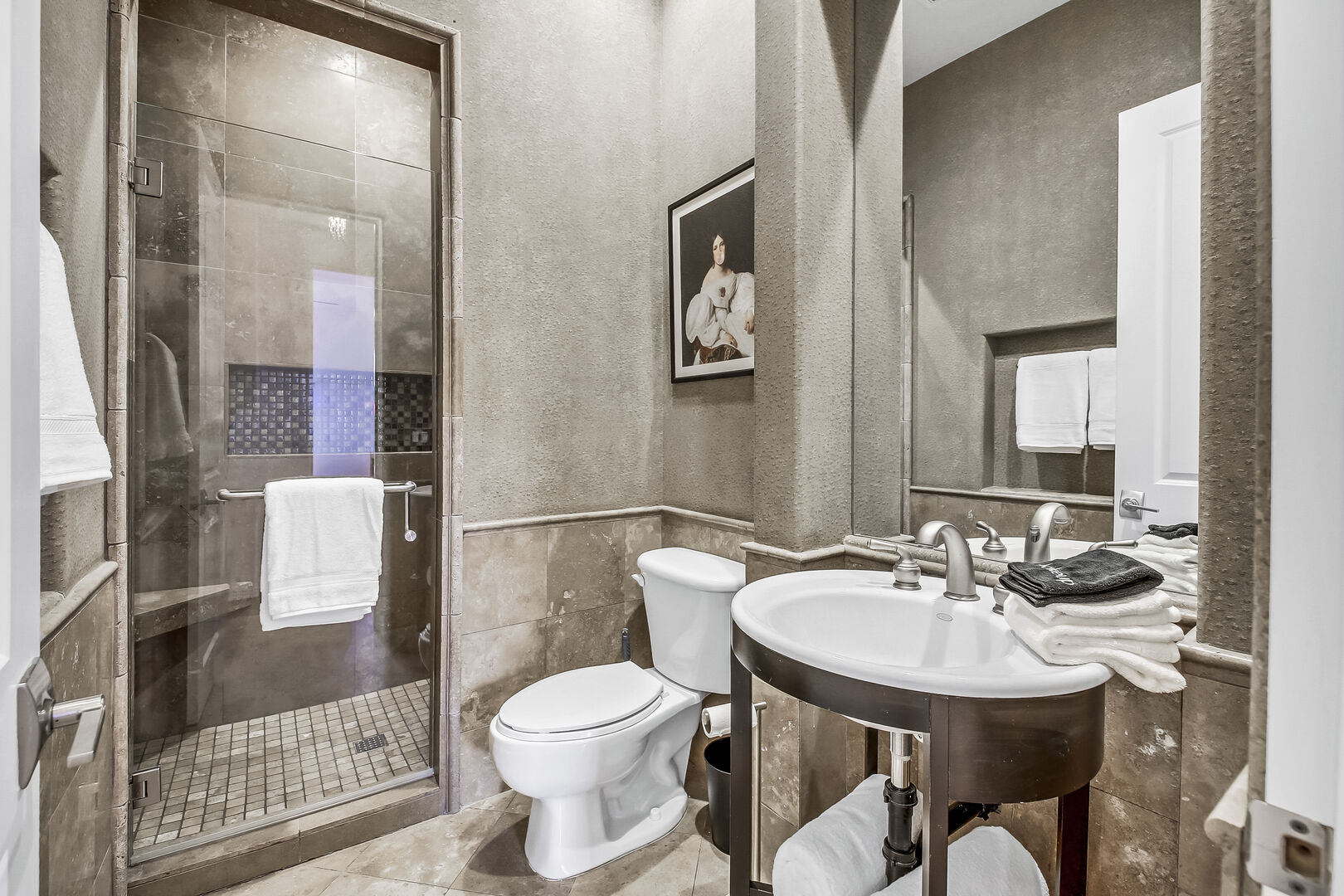 The hallway bathroom is located near the front door and features a tile shower and pedestal sink.