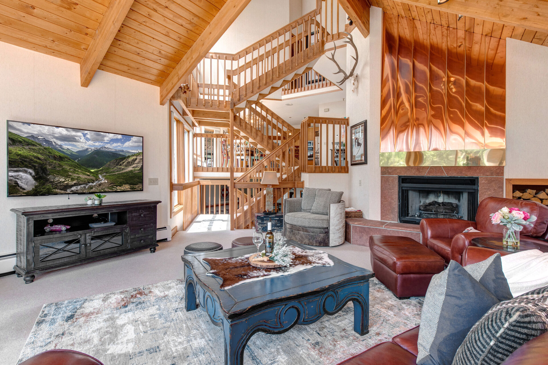 Living Room with plush leather furniture, smart TV, gas fireplace, and private, wrap-around deck access