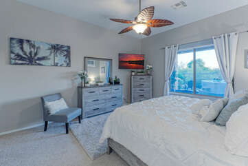 Primary suite with king bed, TV and ensuite bath has views of the backyard amenities.