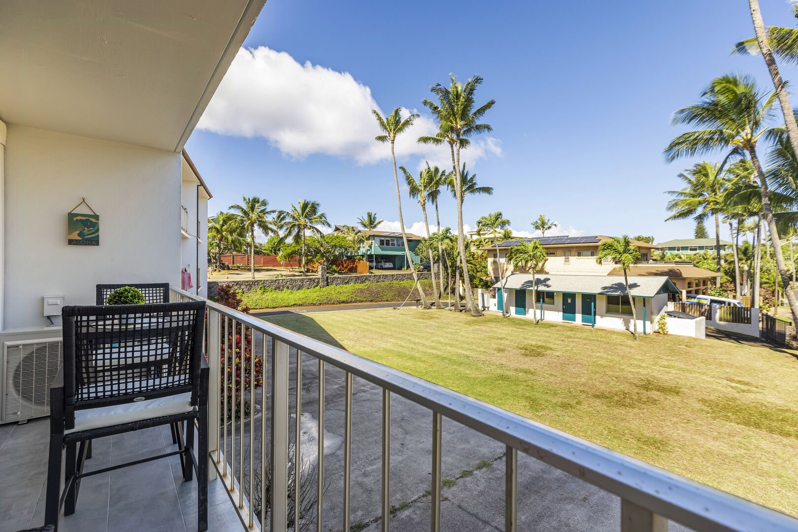 Balcony with views of the backyard of the building and Kuau Cove with many palm trees