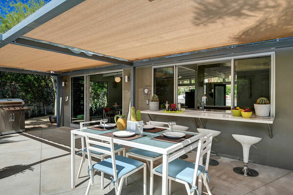 OPEN KITCHEN WITH SLIDER WINDOW MAKING AN OUTDOOR BAR WITH SEATING