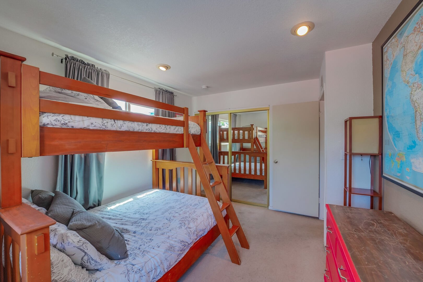 Second private guest bedroom with bunk bed with twin and full beds, dresser, and mirrored closet