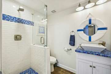 Custom tiled bathroom adjacent to the bunk area with stand up shower, commode and vanity,