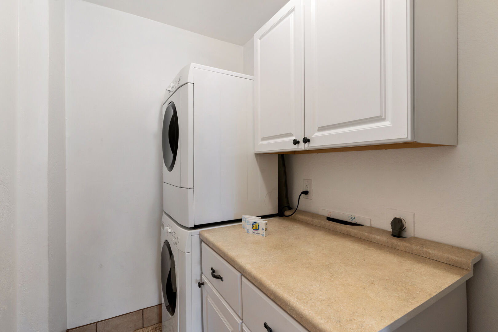 in- unit laundry room has a stacked washer and dryer.