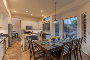 Enjoy the wonderful view of the backyard oasis at the dining table with bench and chair seating.