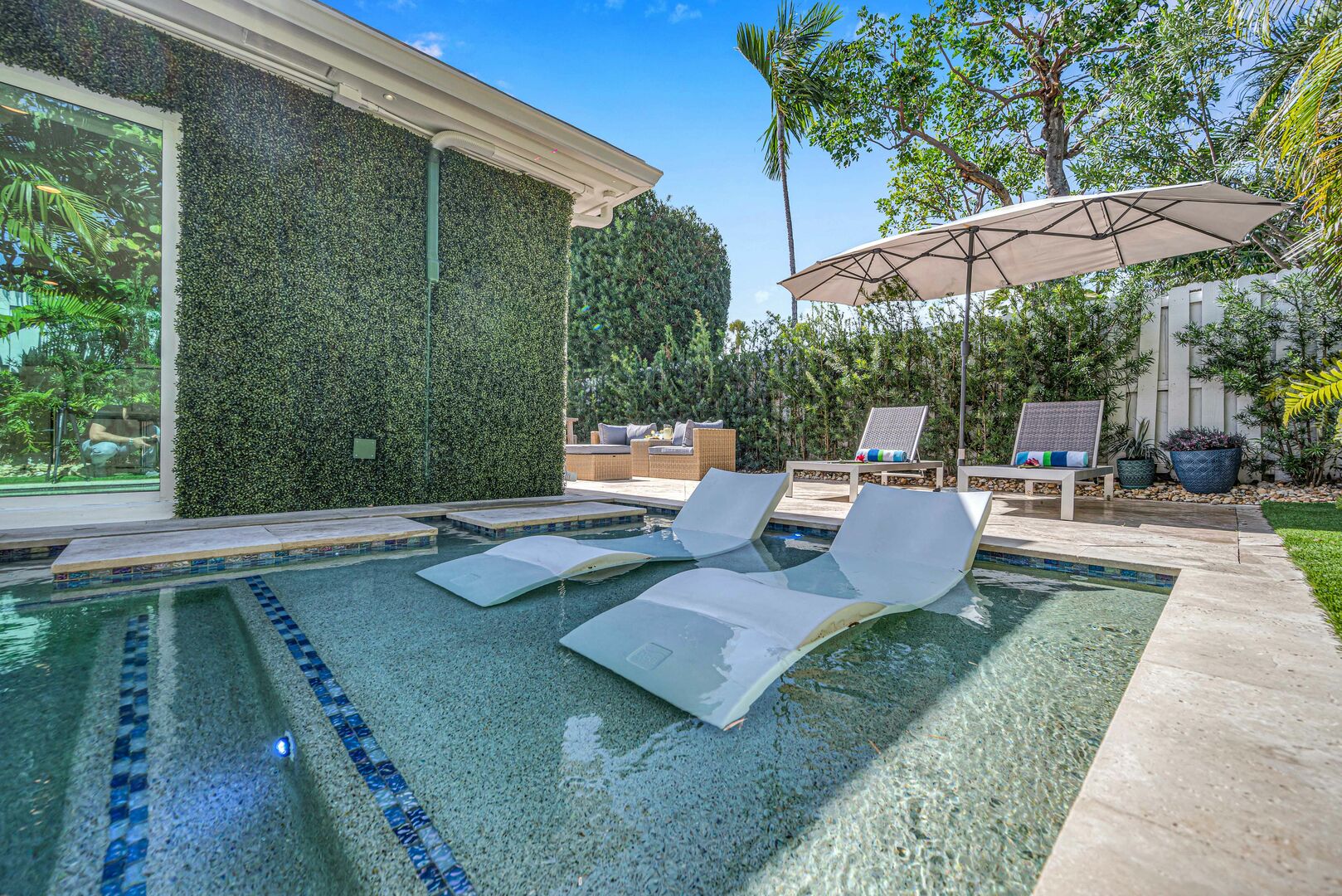 The lush garden oasis features a heated pool with its tanning shelf, two lounger areas, dining space and grill.
