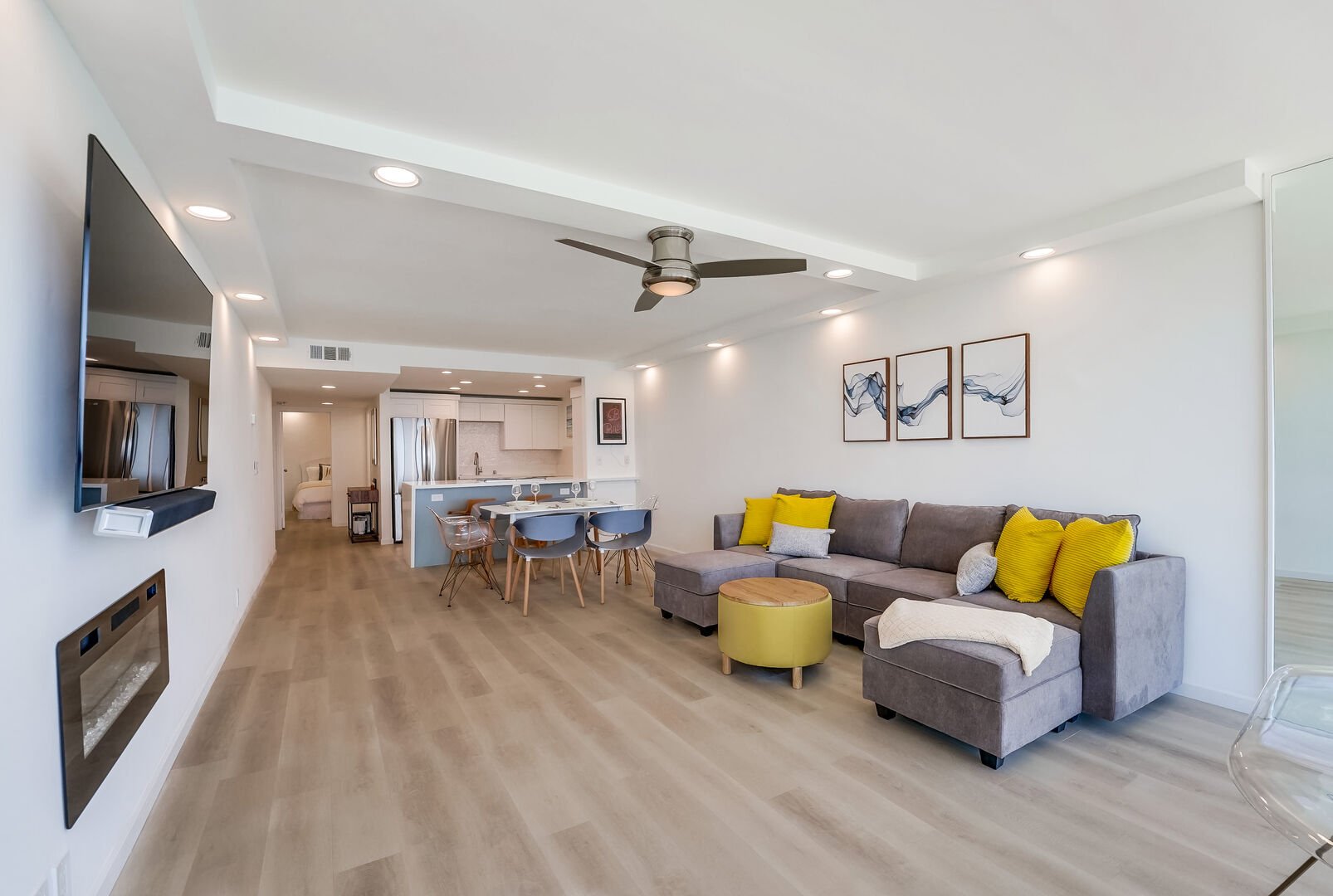 Living space includes sofa, electric fireplace, ceiling fan, smart TV, dining table for 4-6, fully equipped kitchen with stainless steel appliances, breakfast bar with 2 stools and bedroom and bathroom toward the front of the unit