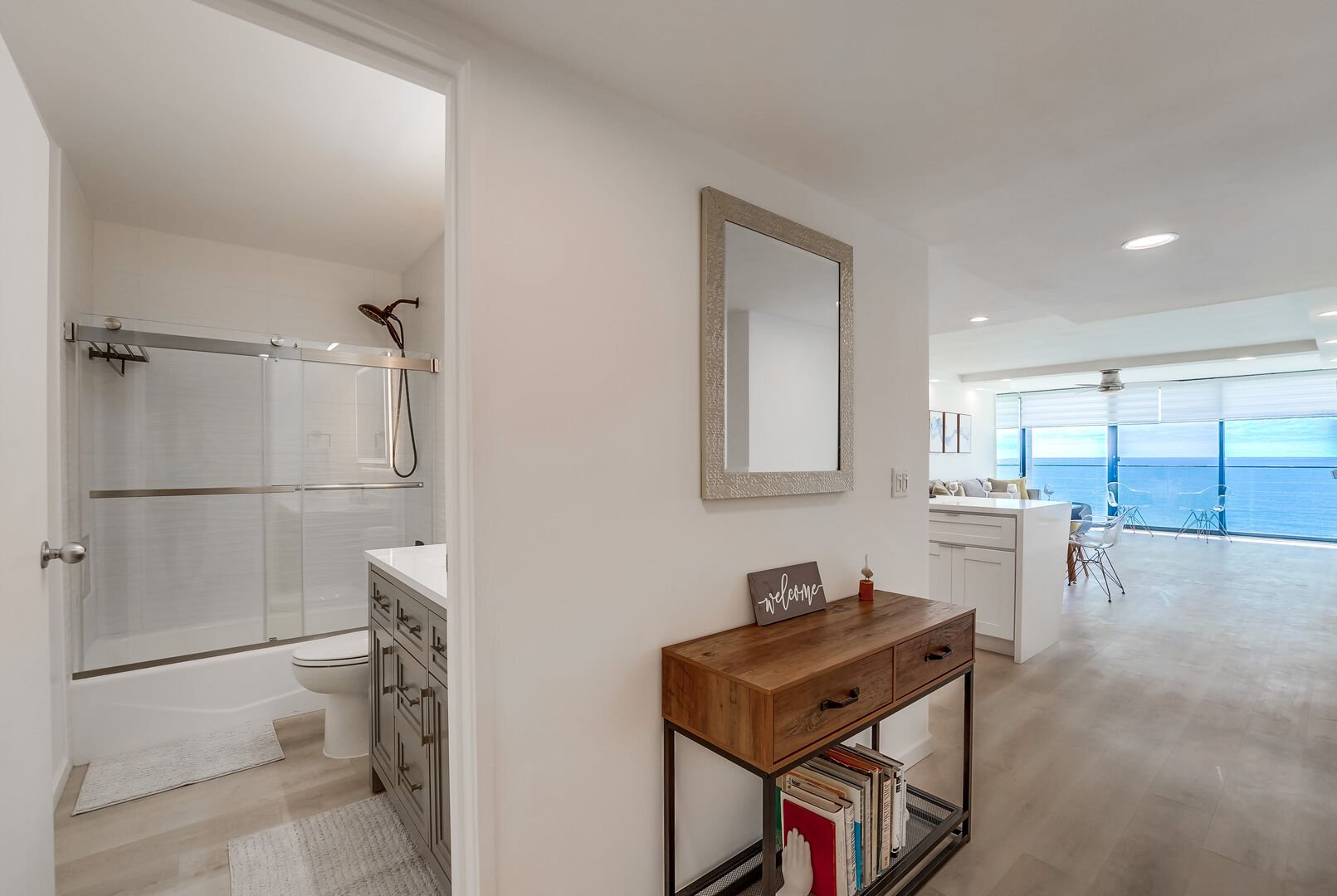 Foyer into the remodeled bathroom with shower/tub combo, spacious vanity, toilet and LED dimmable smart mirror