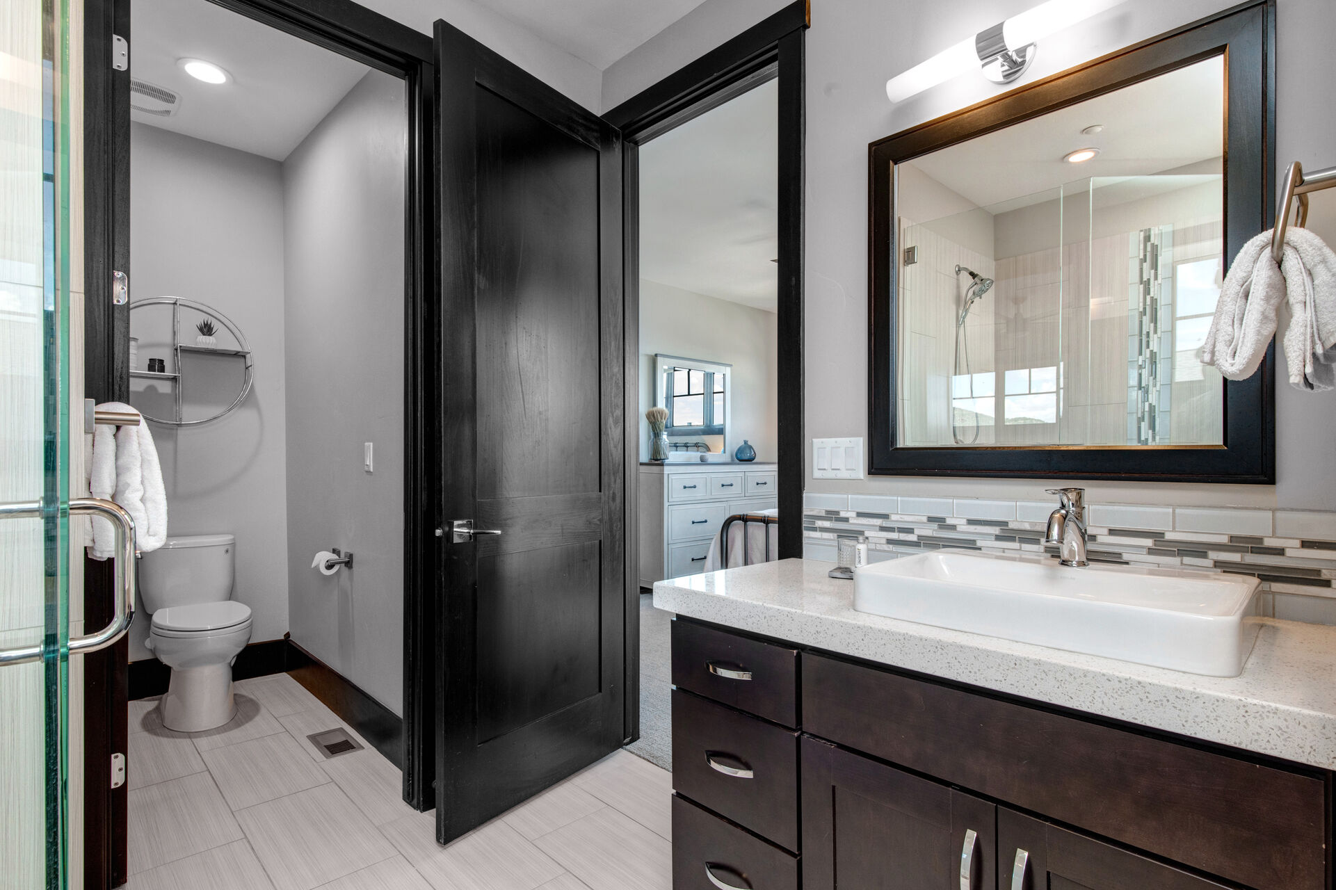 Master Bathroom with two separate vanities, over-sized tile & glass shower, and private wash room
