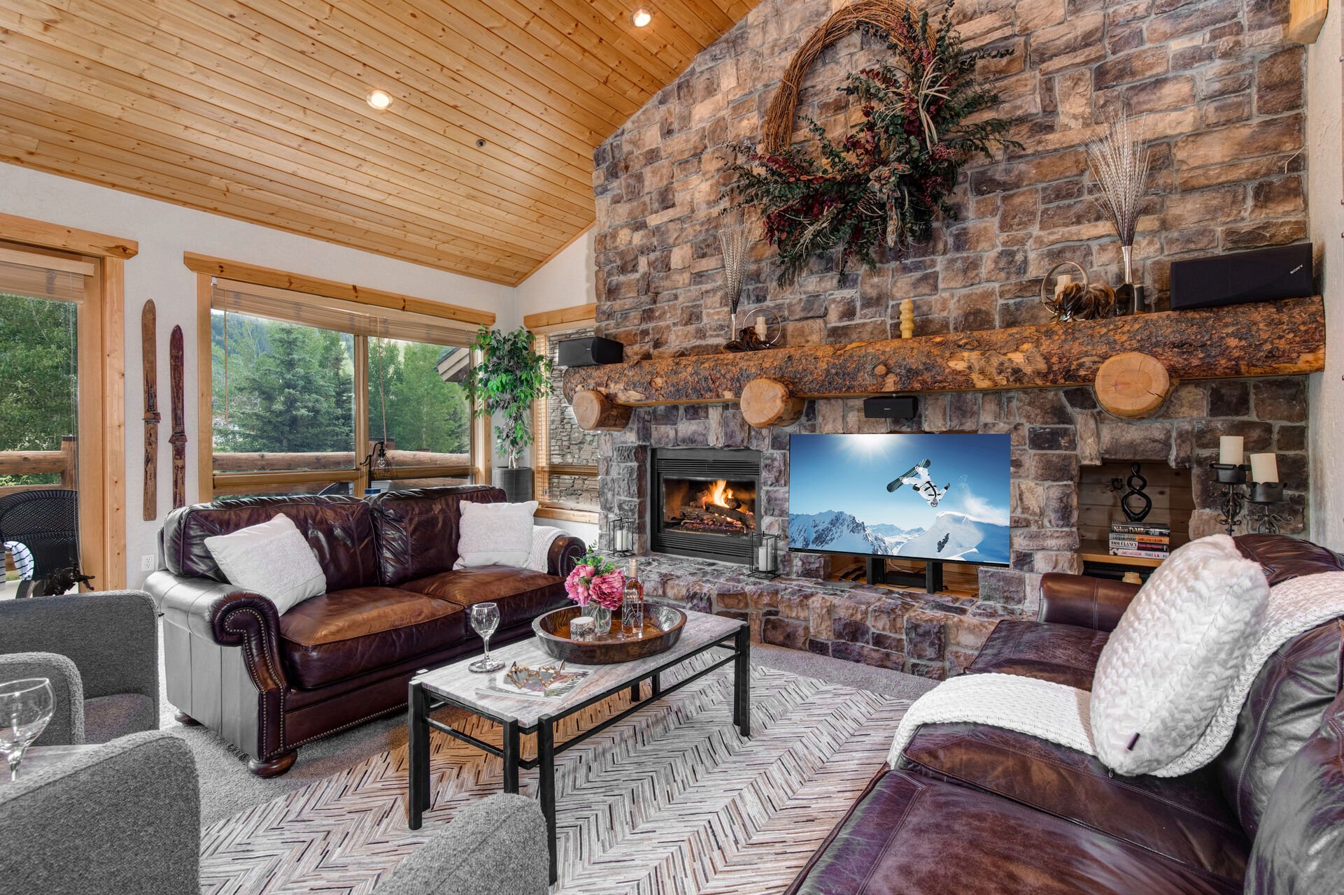 Main Level Living Room with plush leather sofas, contemporary arm chairs, smart tv, gas fireplace, vaulted ceilings, and private hot tub patio access