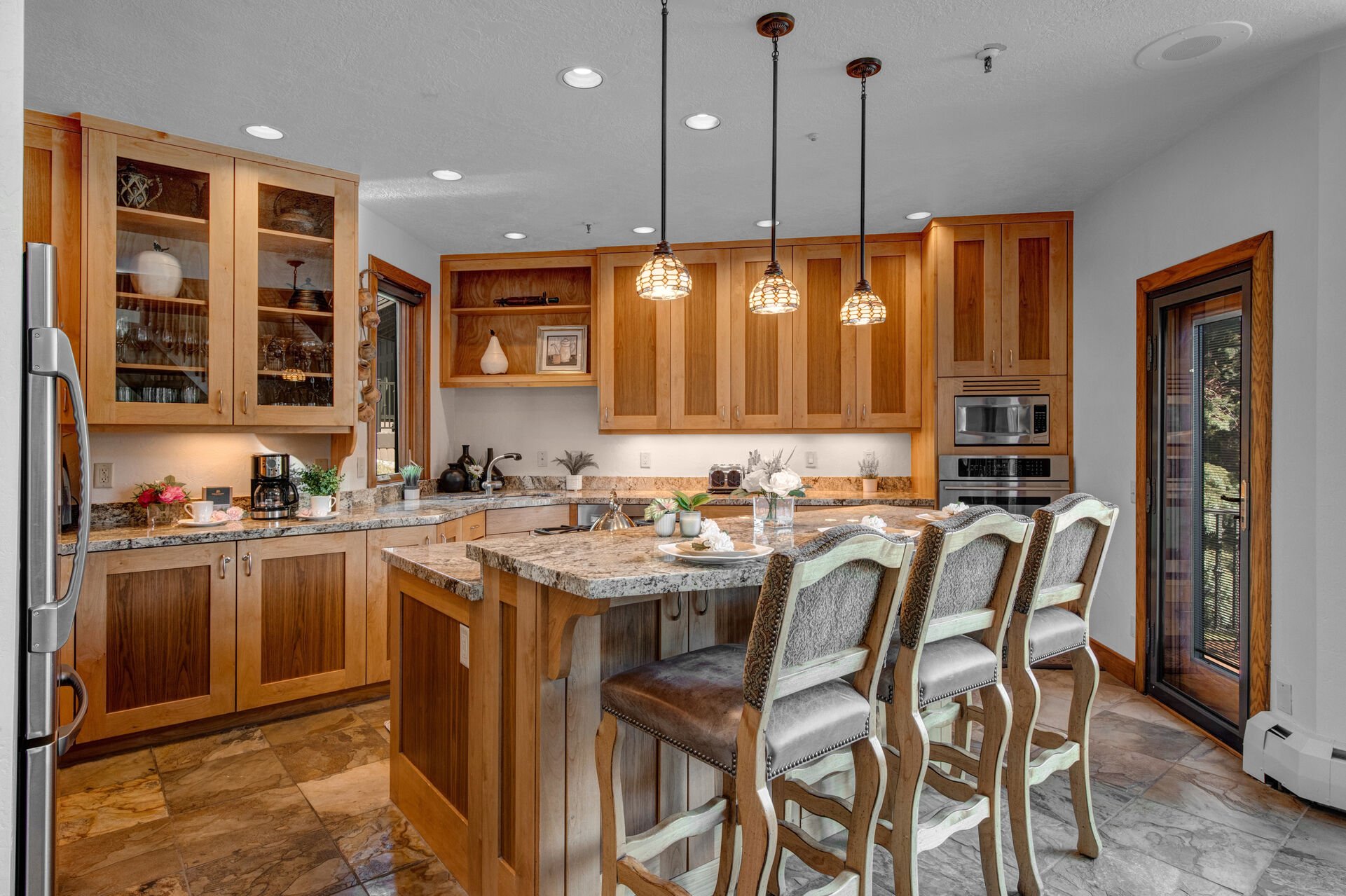 Fully Equipped Kitchen with gorgeous stone countertops, stainless steel appliances, private deck access, and island seating for 3