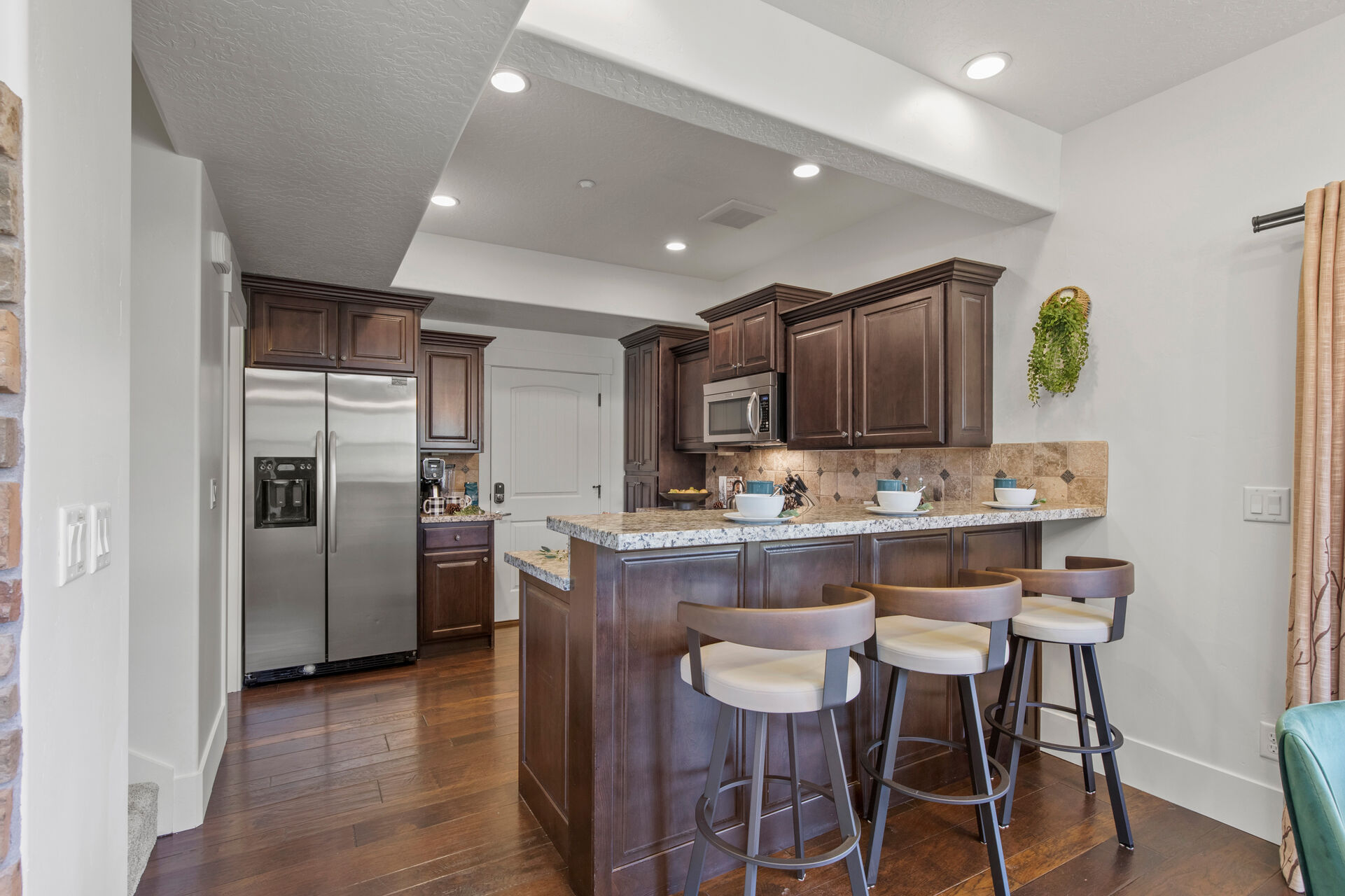 Fully equipped kitchen with stone countertops, stainless steel appliances, and bar seating for 3