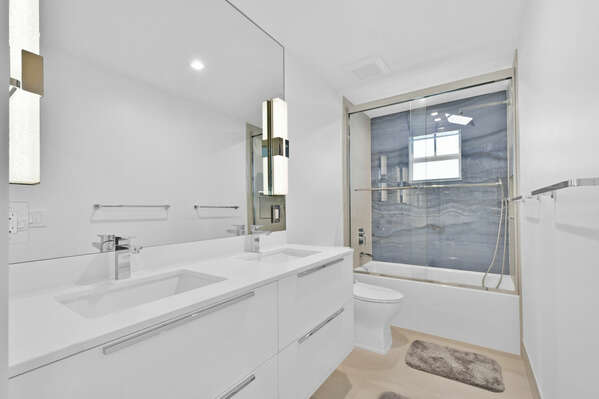 Guest bathroom with shower over tub, twin sinks