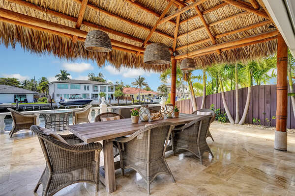 Outdoor dining under tiki hut with fans, lights, BBQ provided