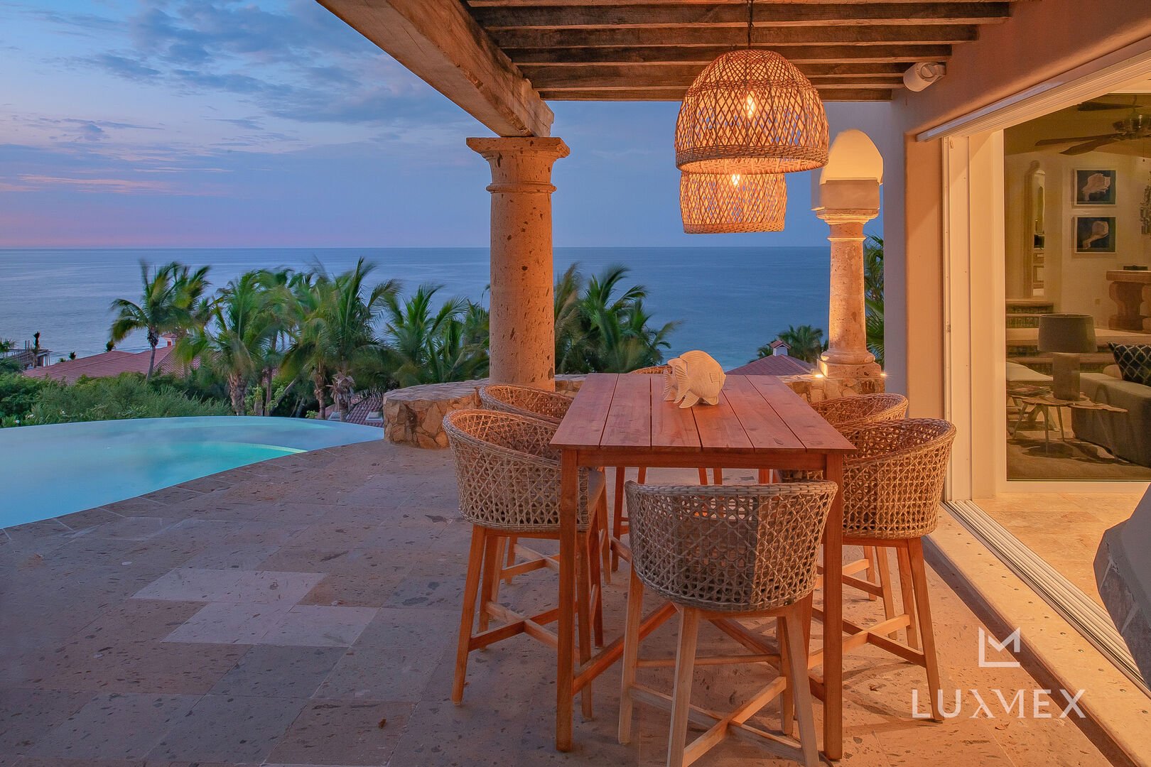 A high table and chairs sits on the patio at sunset.
