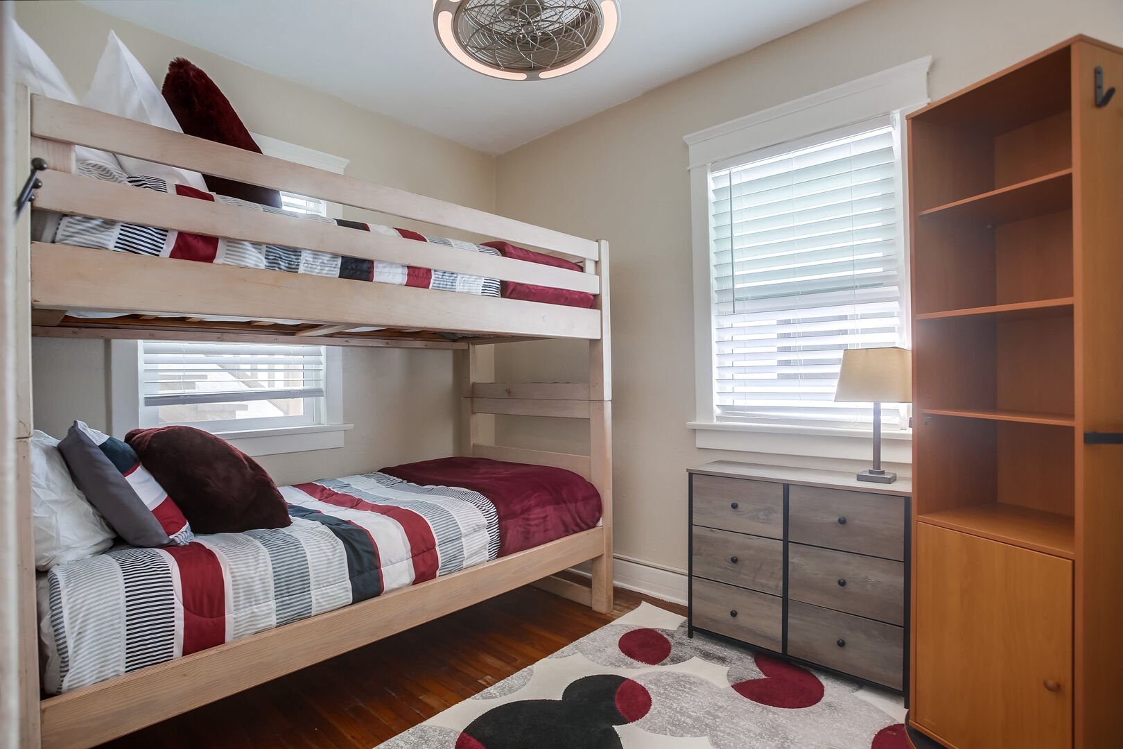 Guest bedroom with twin bunk beds, ceiling fan, dresser and small closet