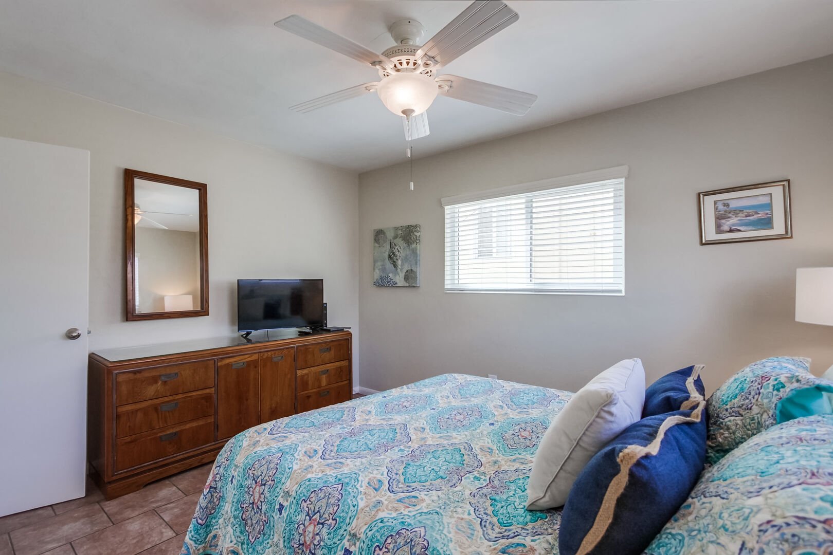 Spacious bedroom with queen size bed, ceiling fan, dresser and closet storage