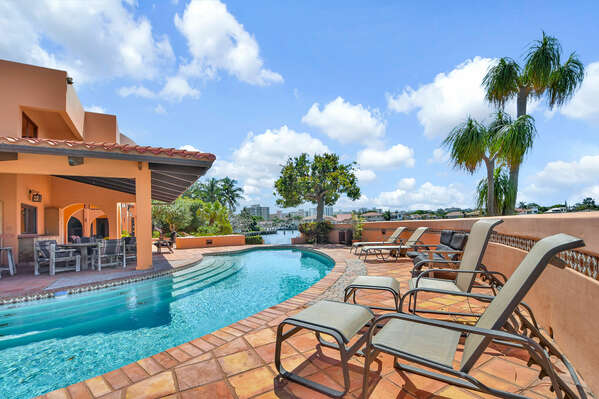 Large patio surrounding pool with furniture, shade and so on.